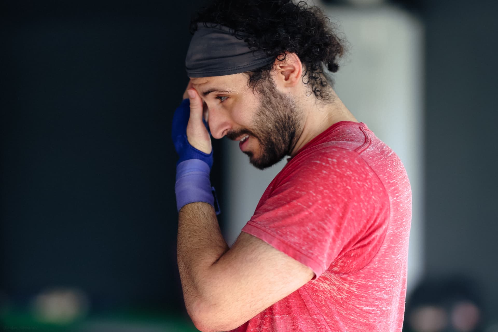A student in a red shirt wiping sweat from his face after a round