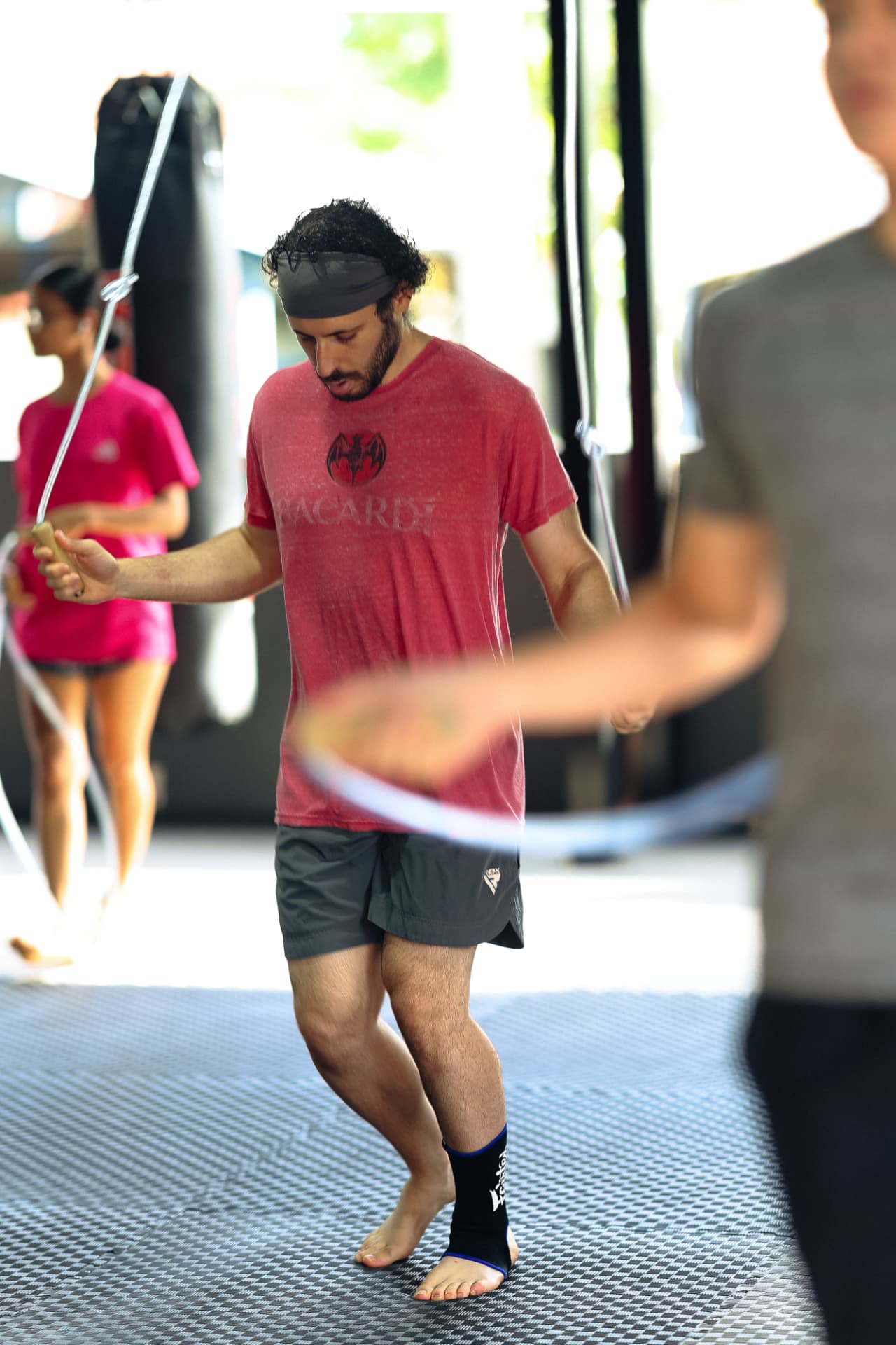 A man in a red shirt skipping rope with other students training behind