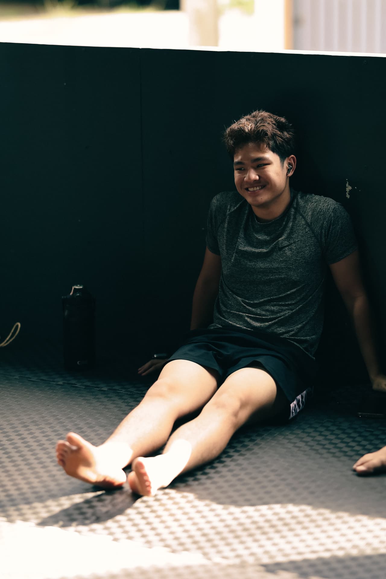 A smiling young fighter sitting on the mats after training