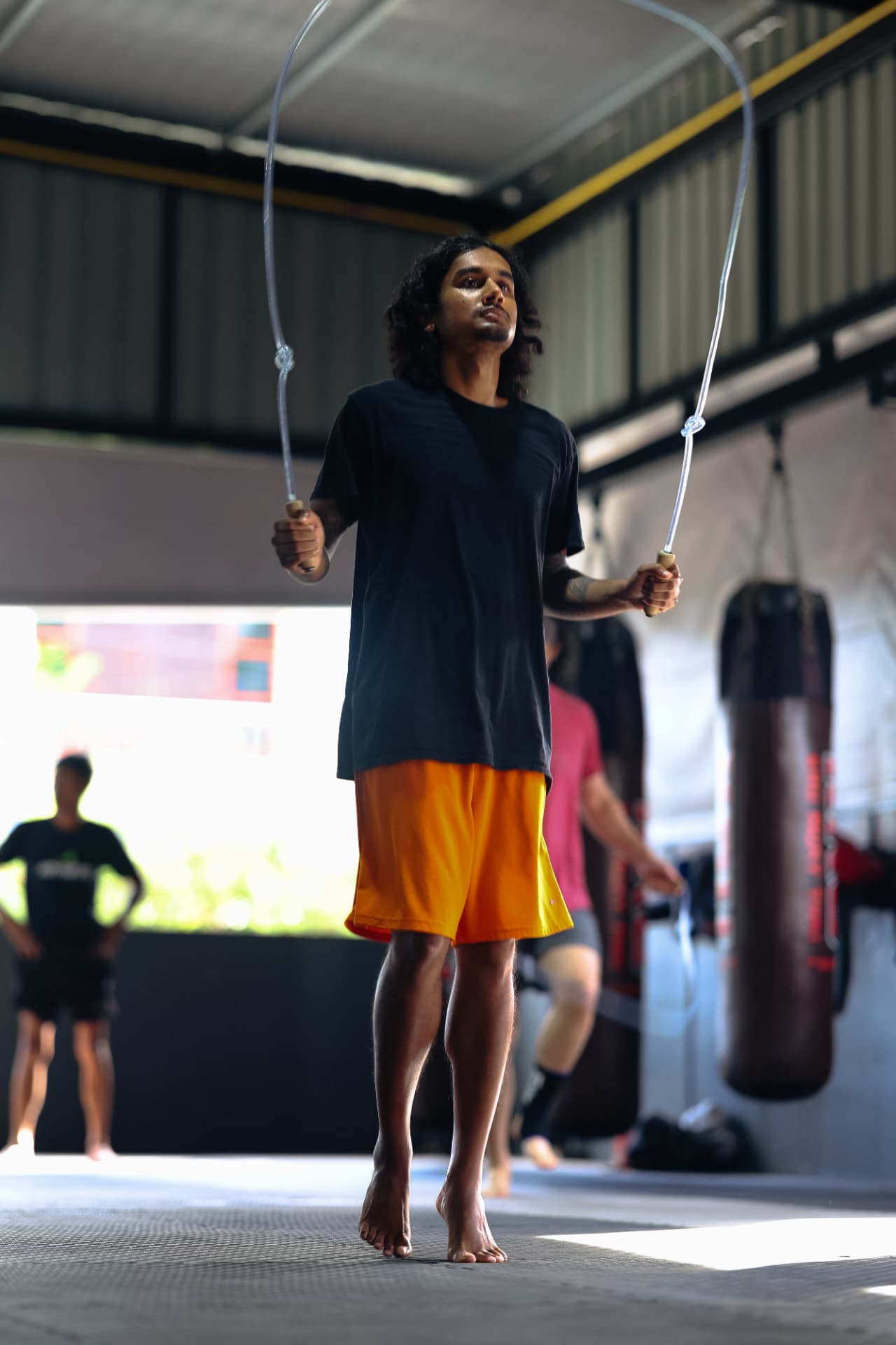 A student in orange shorts skipping rope on the training floor