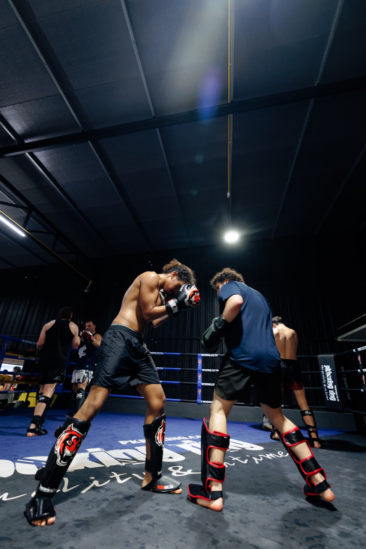 Two fighters in shin guards trading strikes during ring sparring