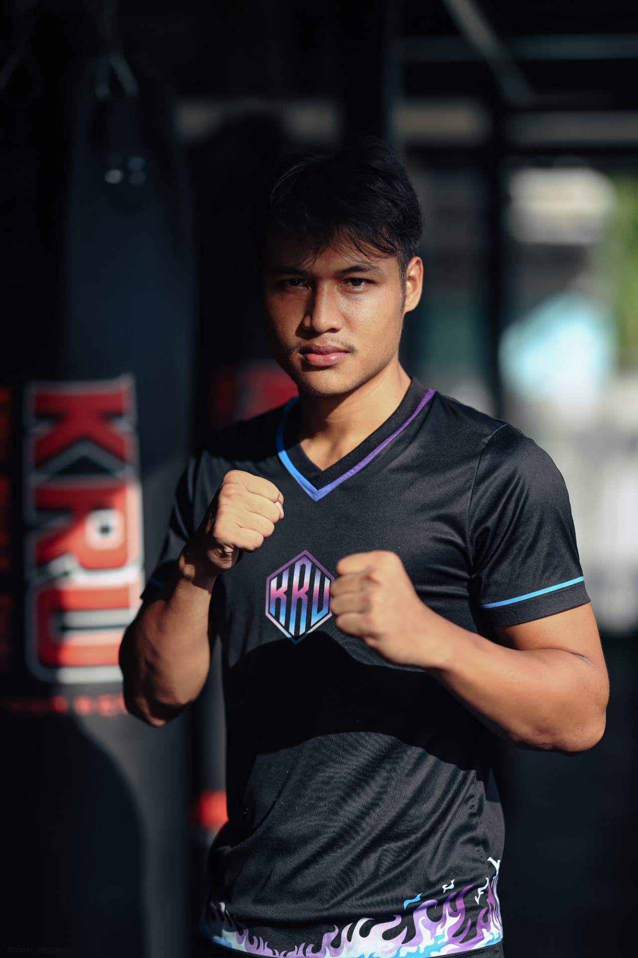 Kru Jo in a black KRU shirt standing in a boxing guard