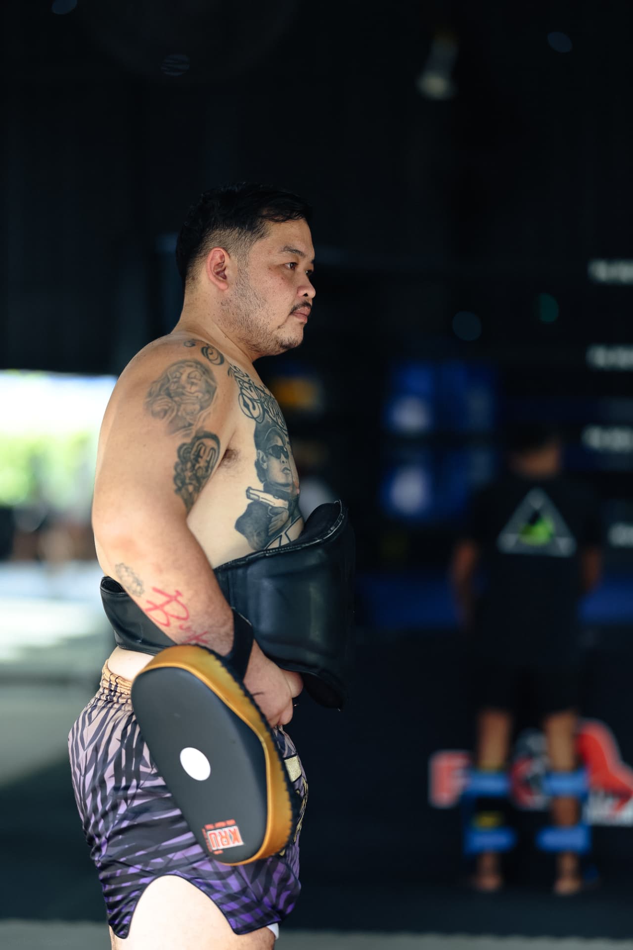 Kru Van holding pads in profile on the gym floor
