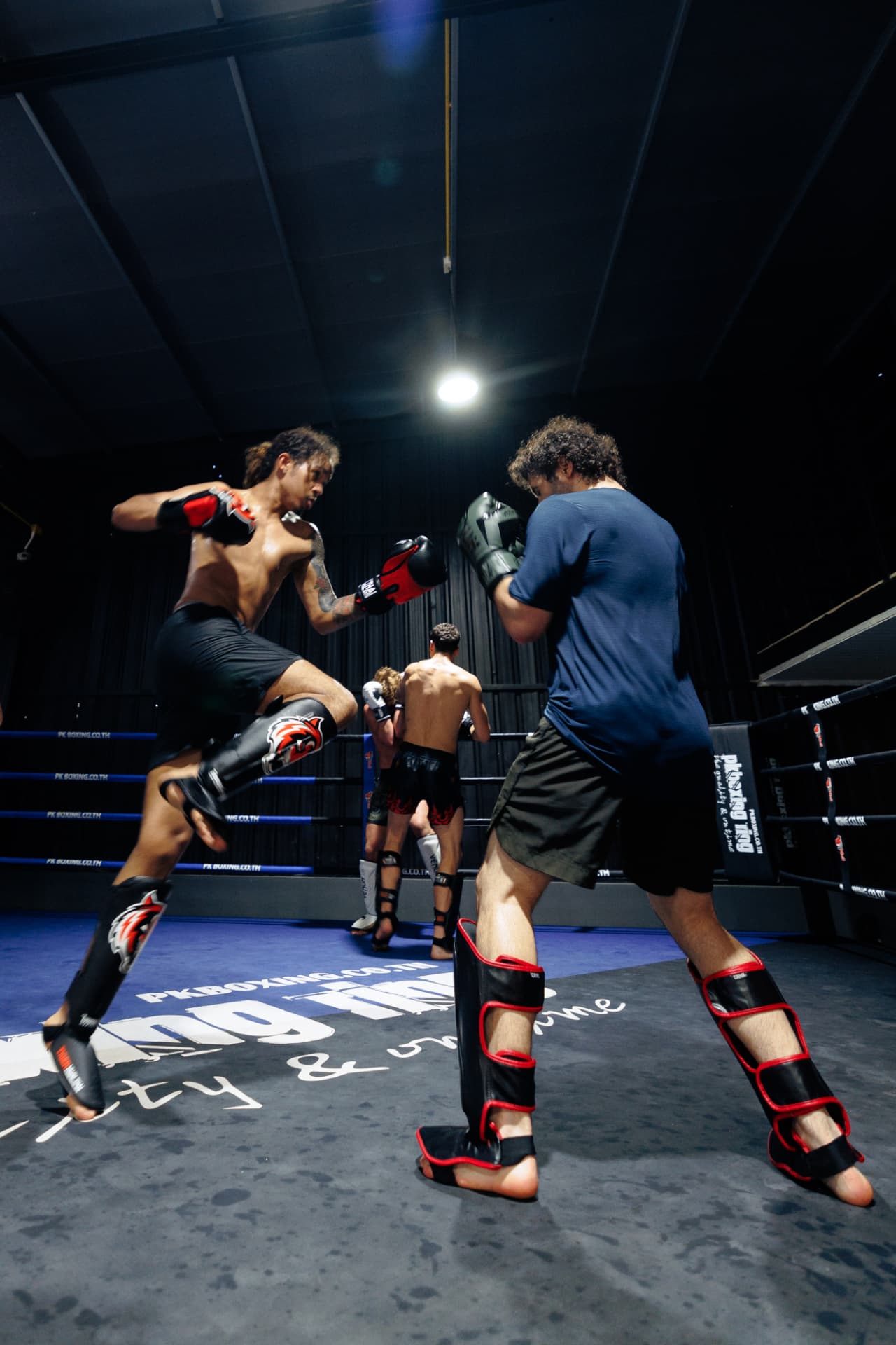 A fighter driving a knee forward while sparring in the ring
