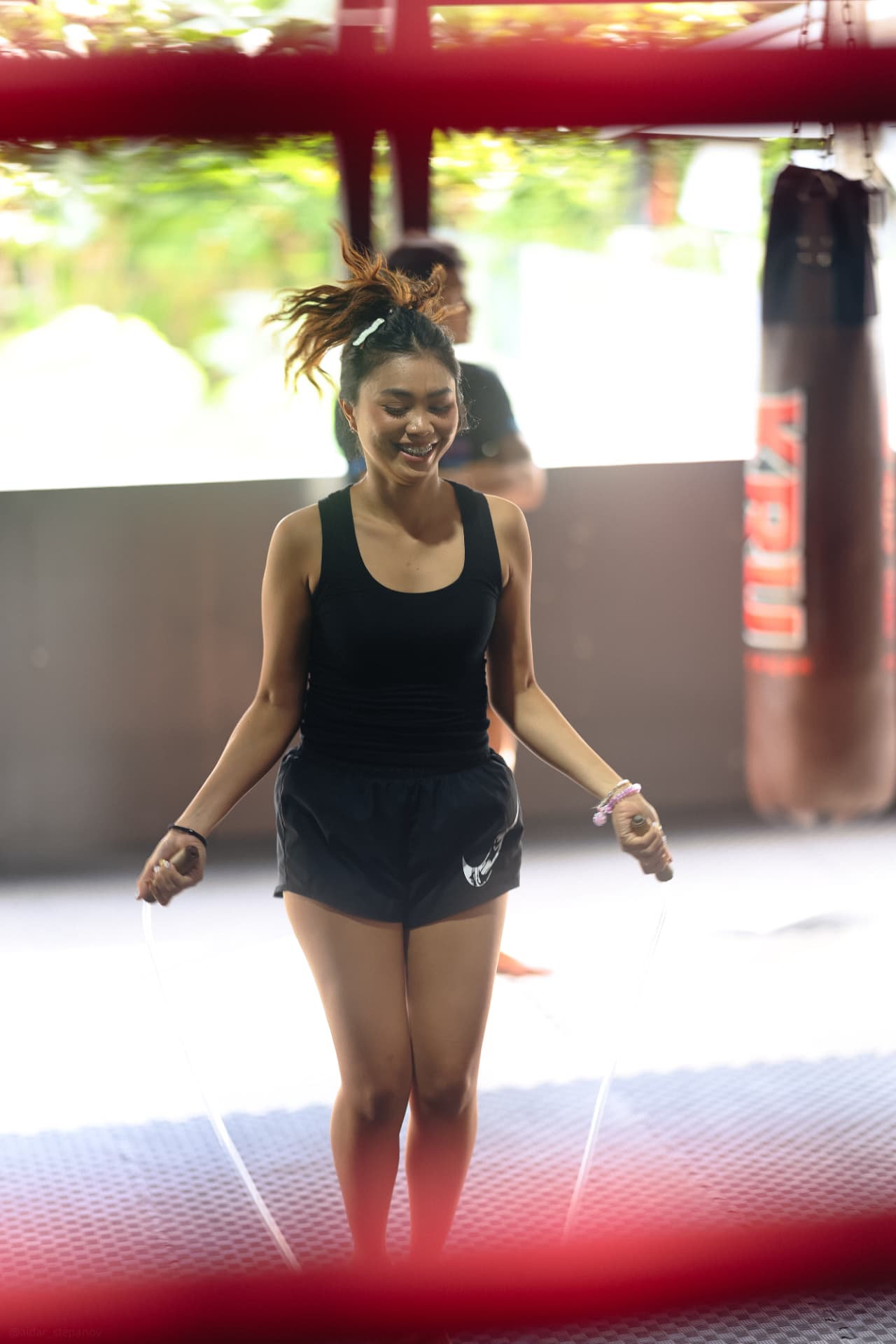 A smiling woman skipping rope beside the ring
